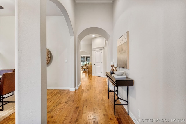 corridor with a towering ceiling and light wood-type flooring