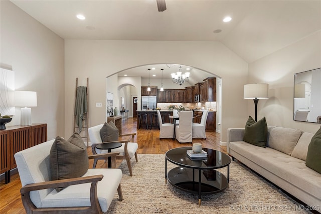 living room featuring wood-type flooring, a chandelier, and vaulted ceiling