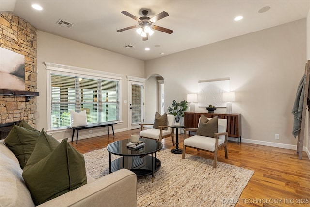 living room featuring a fireplace, ceiling fan, and light hardwood / wood-style flooring