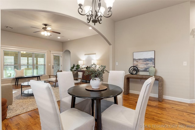 dining room with ceiling fan with notable chandelier and light hardwood / wood-style flooring