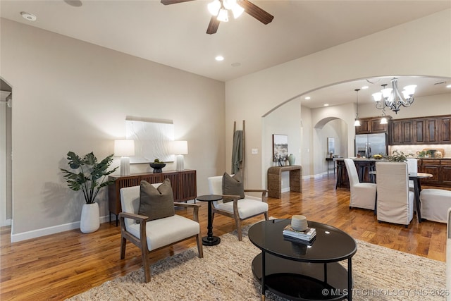 living room featuring ceiling fan with notable chandelier and wood-type flooring