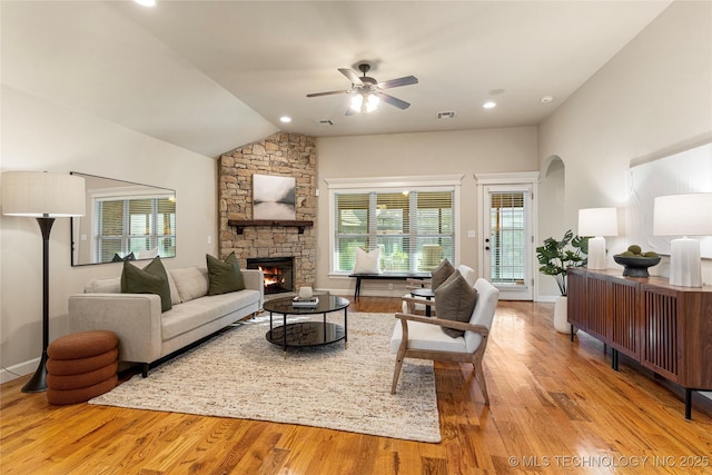 living room featuring ceiling fan, light hardwood / wood-style flooring, lofted ceiling, and a fireplace