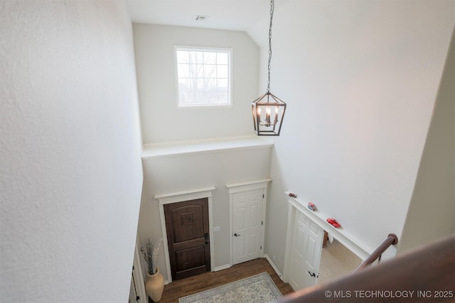 stairs featuring hardwood / wood-style floors, lofted ceiling, and an inviting chandelier