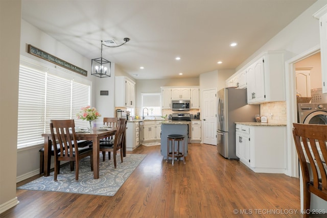 dining area featuring sink, washer / dryer, dark hardwood / wood-style flooring, and a notable chandelier