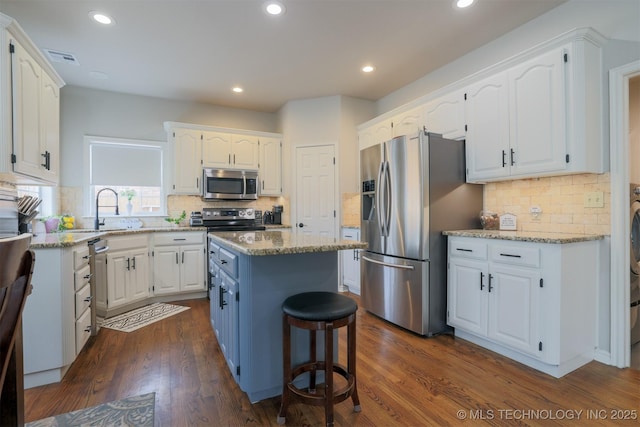 kitchen featuring white cabinets, backsplash, stainless steel appliances, and a center island