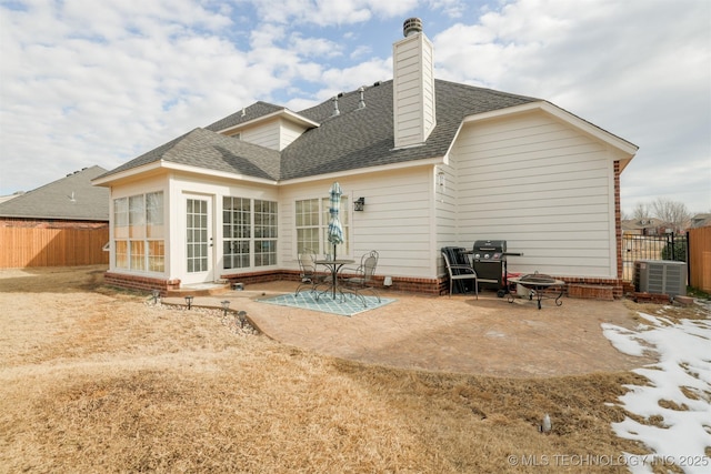 back of property featuring central air condition unit, an outdoor fire pit, a patio, and a sunroom