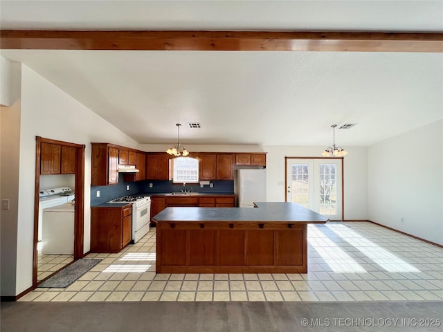 kitchen featuring fridge, white gas stove, a center island, tasteful backsplash, and pendant lighting