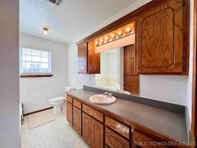 bathroom featuring toilet, a textured ceiling, and vanity