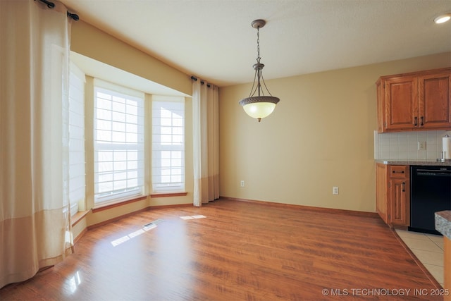 kitchen featuring decorative light fixtures, plenty of natural light, backsplash, and dishwasher