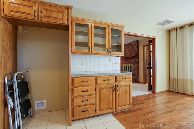 kitchen featuring a fireplace, light stone countertops, light tile patterned floors, and tasteful backsplash