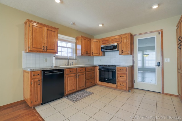 kitchen with decorative backsplash, sink, light tile patterned floors, and black appliances