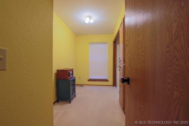 corridor featuring light colored carpet