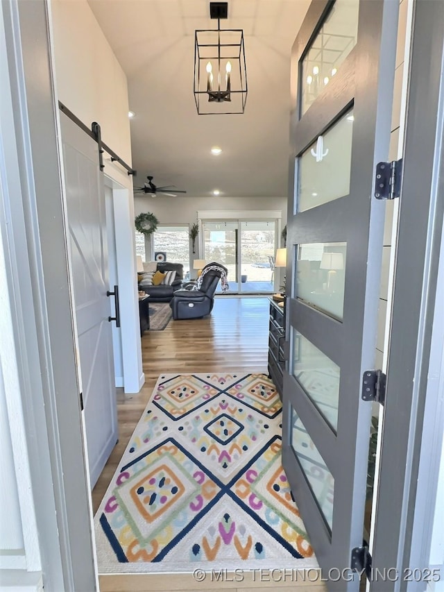 corridor featuring a notable chandelier, a barn door, and hardwood / wood-style floors