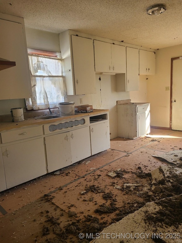 kitchen with a textured ceiling and white cabinets