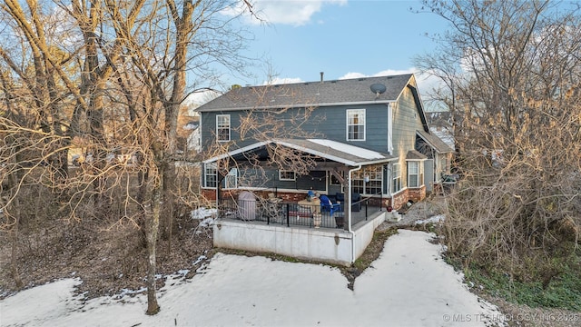 snow covered back of property with a porch