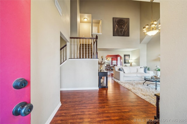 entryway with a high ceiling, an inviting chandelier, and dark hardwood / wood-style floors