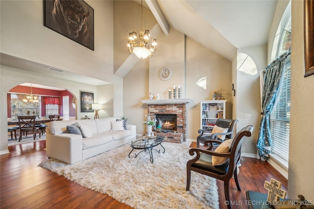 living room featuring dark hardwood / wood-style floors, a notable chandelier, high vaulted ceiling, a fireplace, and beamed ceiling