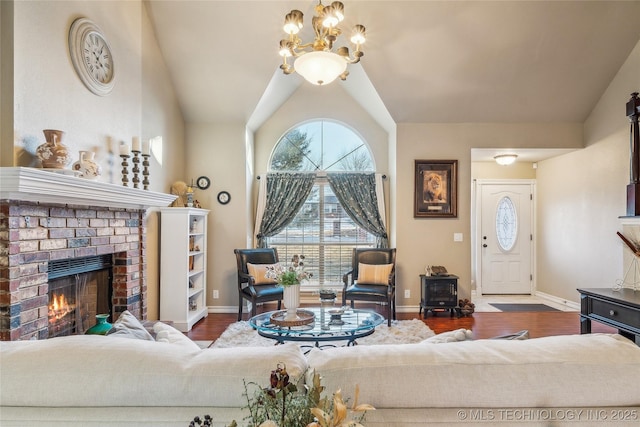 living room featuring hardwood / wood-style floors, a fireplace, a chandelier, and vaulted ceiling