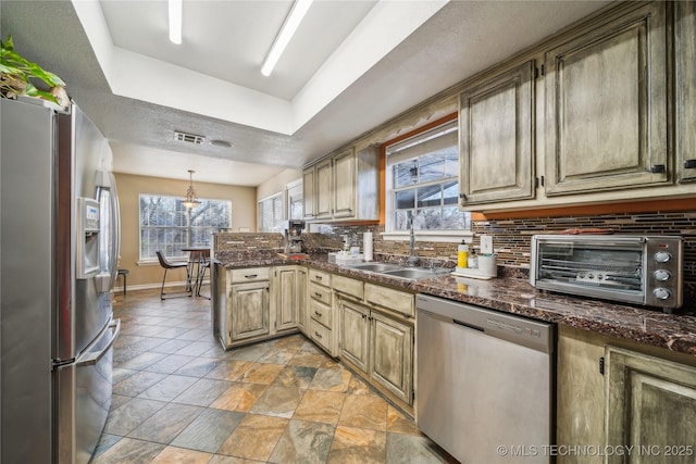 kitchen featuring stainless steel appliances, sink, backsplash, hanging light fixtures, and a tray ceiling