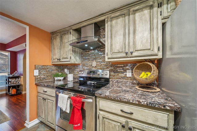 kitchen featuring wall chimney exhaust hood, decorative backsplash, dark hardwood / wood-style flooring, dark stone counters, and appliances with stainless steel finishes