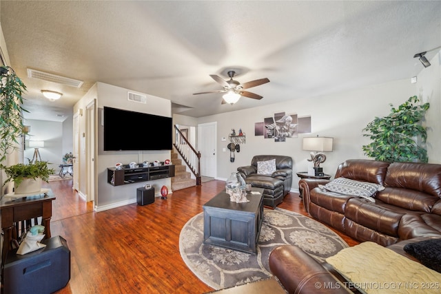 living room with ceiling fan, dark wood-type flooring, and a textured ceiling