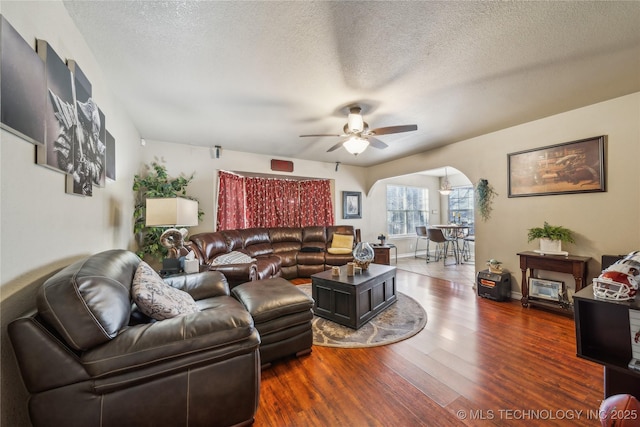 living room featuring wood-type flooring, a textured ceiling, and ceiling fan