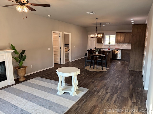 living room with ceiling fan with notable chandelier and dark hardwood / wood-style floors