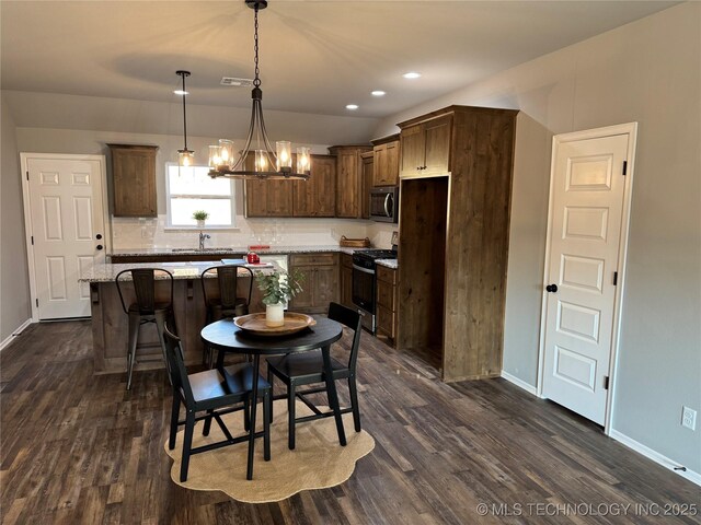 dining room with dark wood-type flooring, an inviting chandelier, and sink