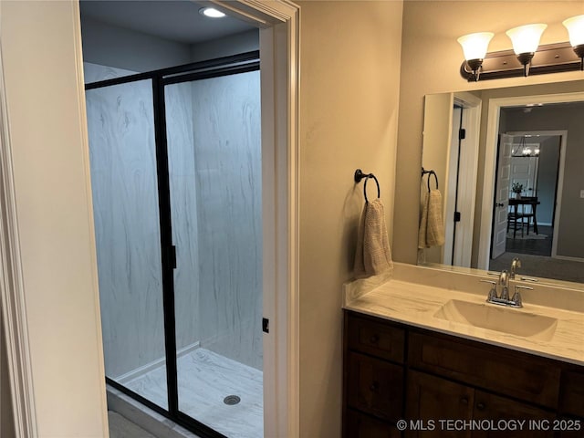 bathroom featuring a shower with door and vanity