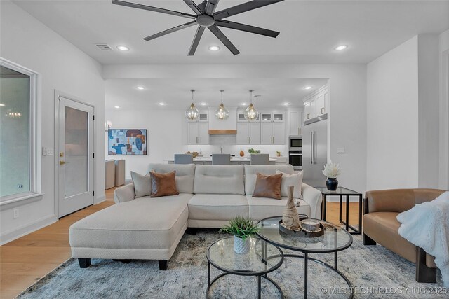 living room with ceiling fan and light hardwood / wood-style flooring