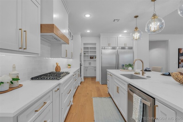 kitchen with white cabinets, appliances with stainless steel finishes, custom exhaust hood, and tasteful backsplash