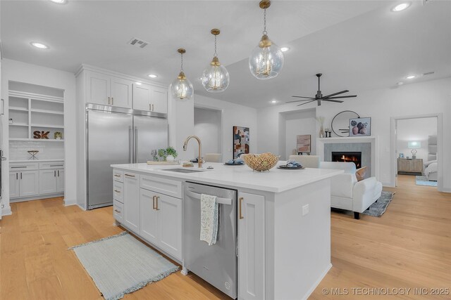 kitchen with stainless steel appliances, white cabinets, sink, and built in features