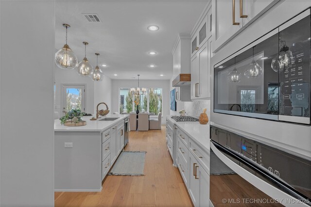 kitchen with stainless steel appliances, white cabinetry, sink, and pendant lighting