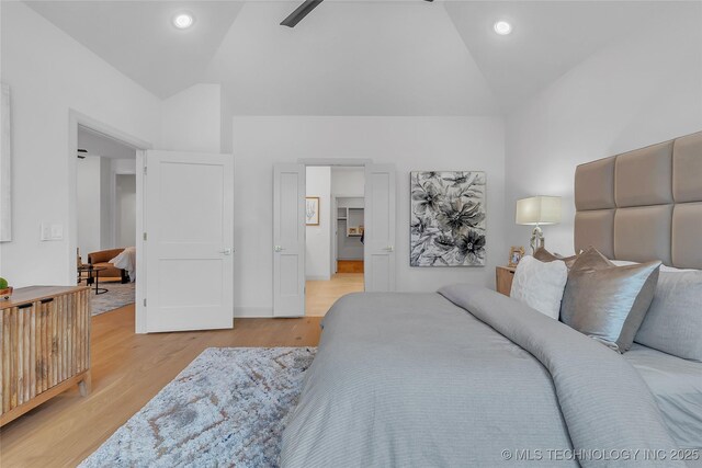 bedroom with ceiling fan, vaulted ceiling, and light hardwood / wood-style floors