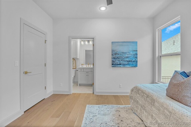 bedroom featuring ensuite bathroom, multiple windows, and light hardwood / wood-style flooring