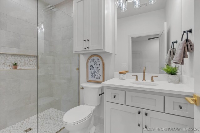 bathroom with toilet, vanity, and tiled shower