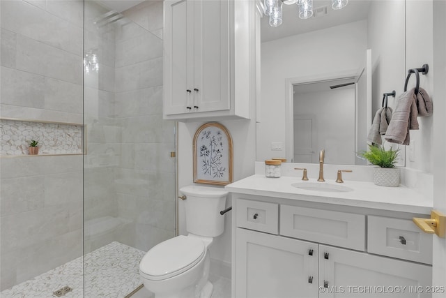 bathroom featuring tiled shower, vanity, and toilet