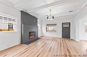 unfurnished living room featuring a fireplace, wood-type flooring, and beamed ceiling