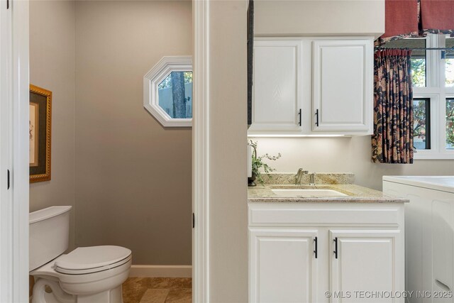 bathroom featuring toilet, washer / dryer, tile patterned floors, and vanity