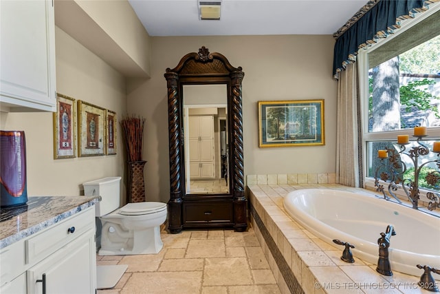 bathroom featuring a relaxing tiled tub, vanity, and toilet