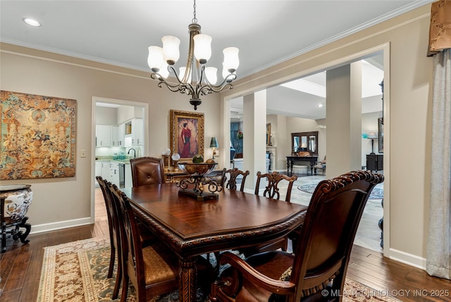 dining space featuring sink, dark hardwood / wood-style flooring, an inviting chandelier, and crown molding