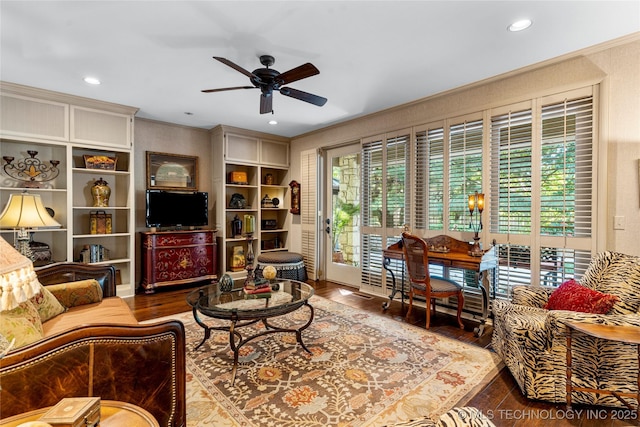 living room with ceiling fan, hardwood / wood-style floors, ornamental molding, and built in shelves