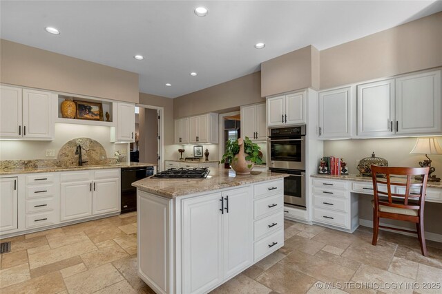 kitchen with appliances with stainless steel finishes, white cabinets, light stone countertops, and a kitchen island