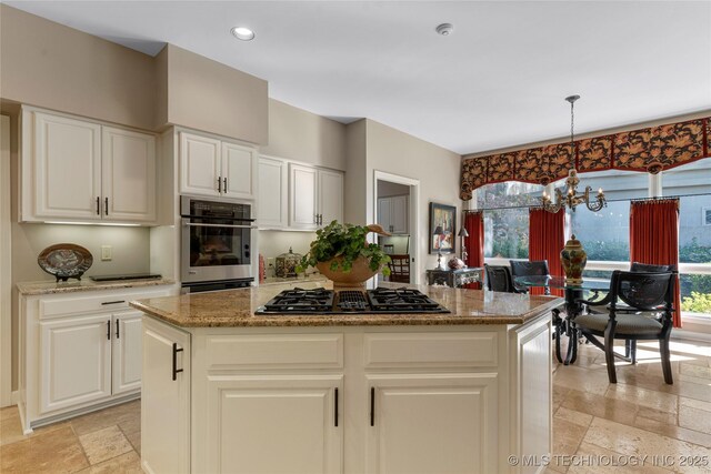 kitchen featuring a chandelier, a center island, pendant lighting, oven, and black gas stovetop