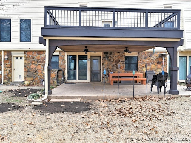 back of property with ceiling fan, a patio area, and a balcony