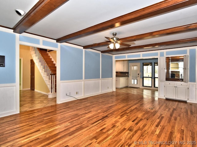 unfurnished living room with ceiling fan, beam ceiling, light hardwood / wood-style floors, and french doors