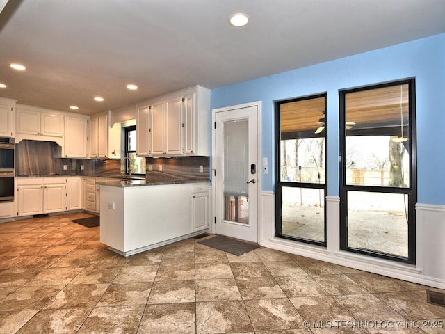 kitchen featuring white cabinets, backsplash, and stainless steel double oven