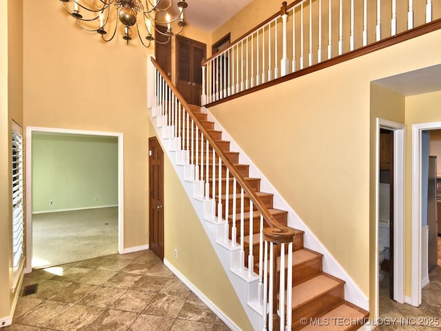 staircase with a chandelier, a towering ceiling, and carpet flooring