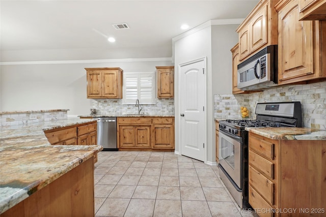 kitchen featuring sink, light tile patterned floors, light stone countertops, crown molding, and appliances with stainless steel finishes