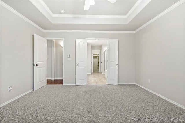 unfurnished bedroom with ceiling fan, crown molding, a raised ceiling, and carpet flooring